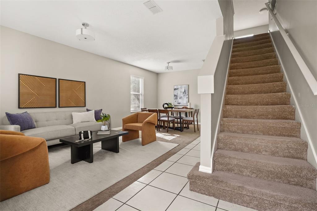 A living and dining area with carpeted stairs, tile flooring, and neutral walls — 14837 HUNTLEY DRIVE, ORLANDO, FL