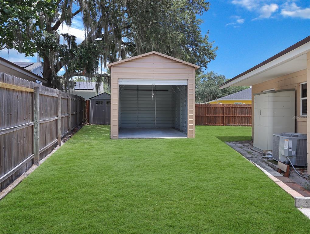 A backyard features a metal shed, a wooden fence, and a small storage unit — 203 SWEETGUM, WINTER SPRINGS, FL