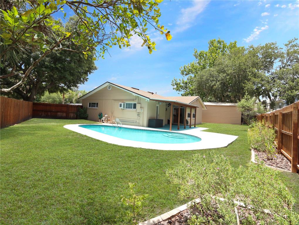 A backyard features a swimming pool, a covered patio, and a wooden privacy fence — 203 SWEETGUM, WINTER SPRINGS, FL