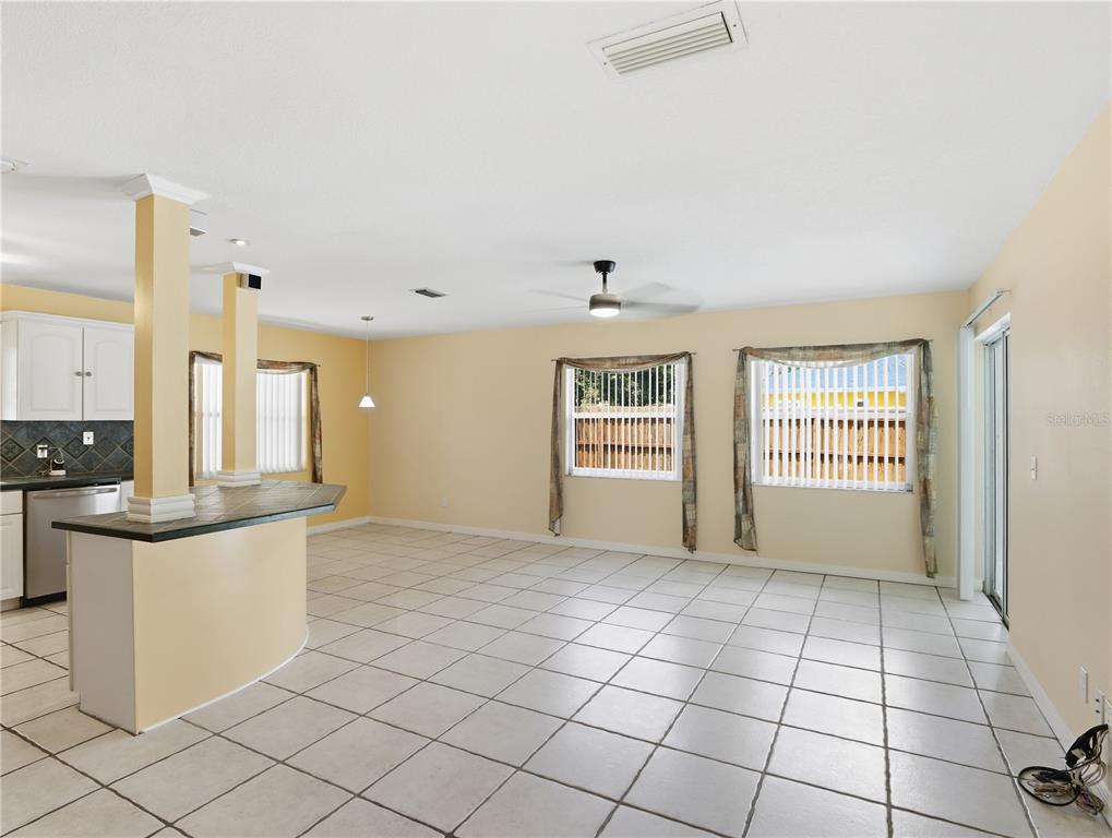 An open-concept room features light-colored tile flooring, a kitchen island, and two windows — 203 SWEETGUM, WINTER SPRINGS, FL