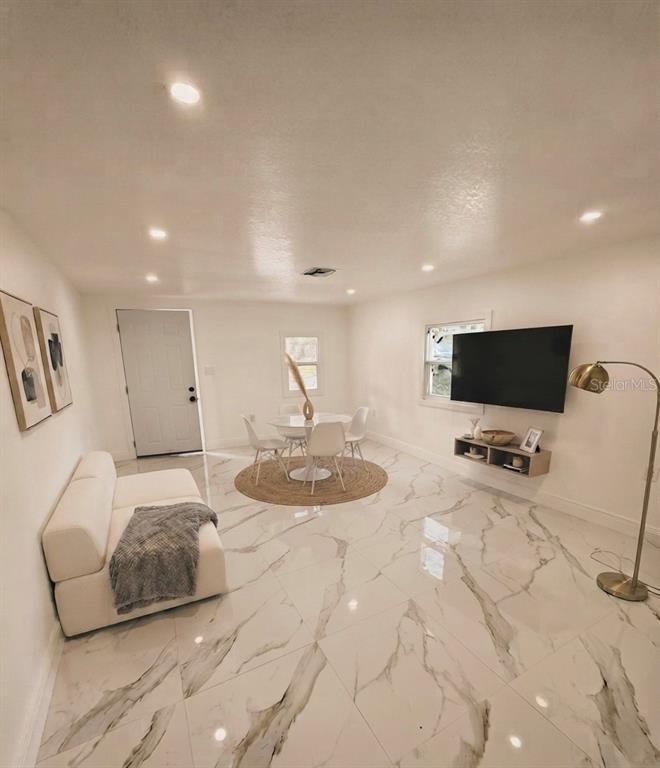 A living and dining area features white marble-look tile flooring, recessed lighting, and a wall-mounted television — 5228 ANDRUS AVENUE, ORLANDO, FL