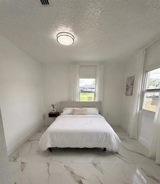 A bedroom features a bed, white walls, a window with curtains, and marble-look tile flooring — 5228 ANDRUS AVENUE, ORLANDO, FL