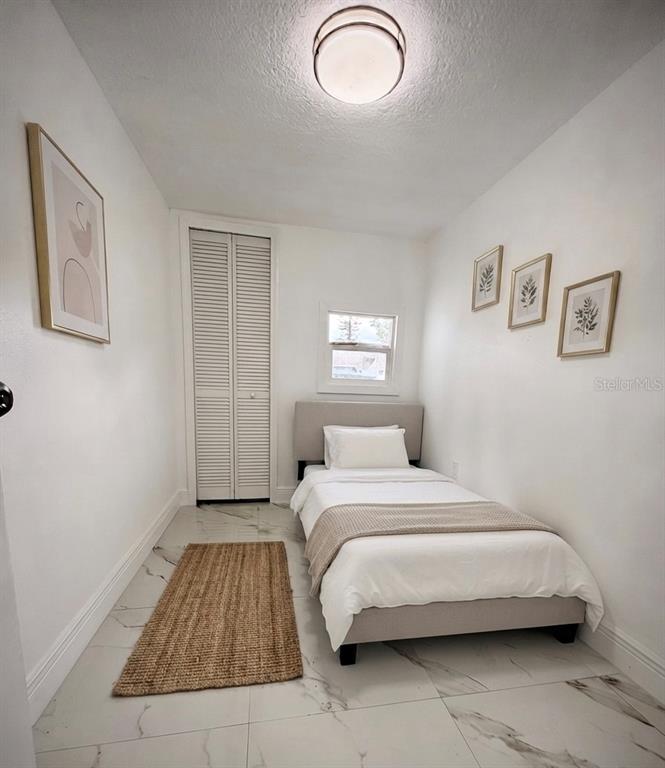 A small bedroom features a twin bed, white walls, tile flooring, and a closet — 5228 ANDRUS AVENUE, ORLANDO, FL
