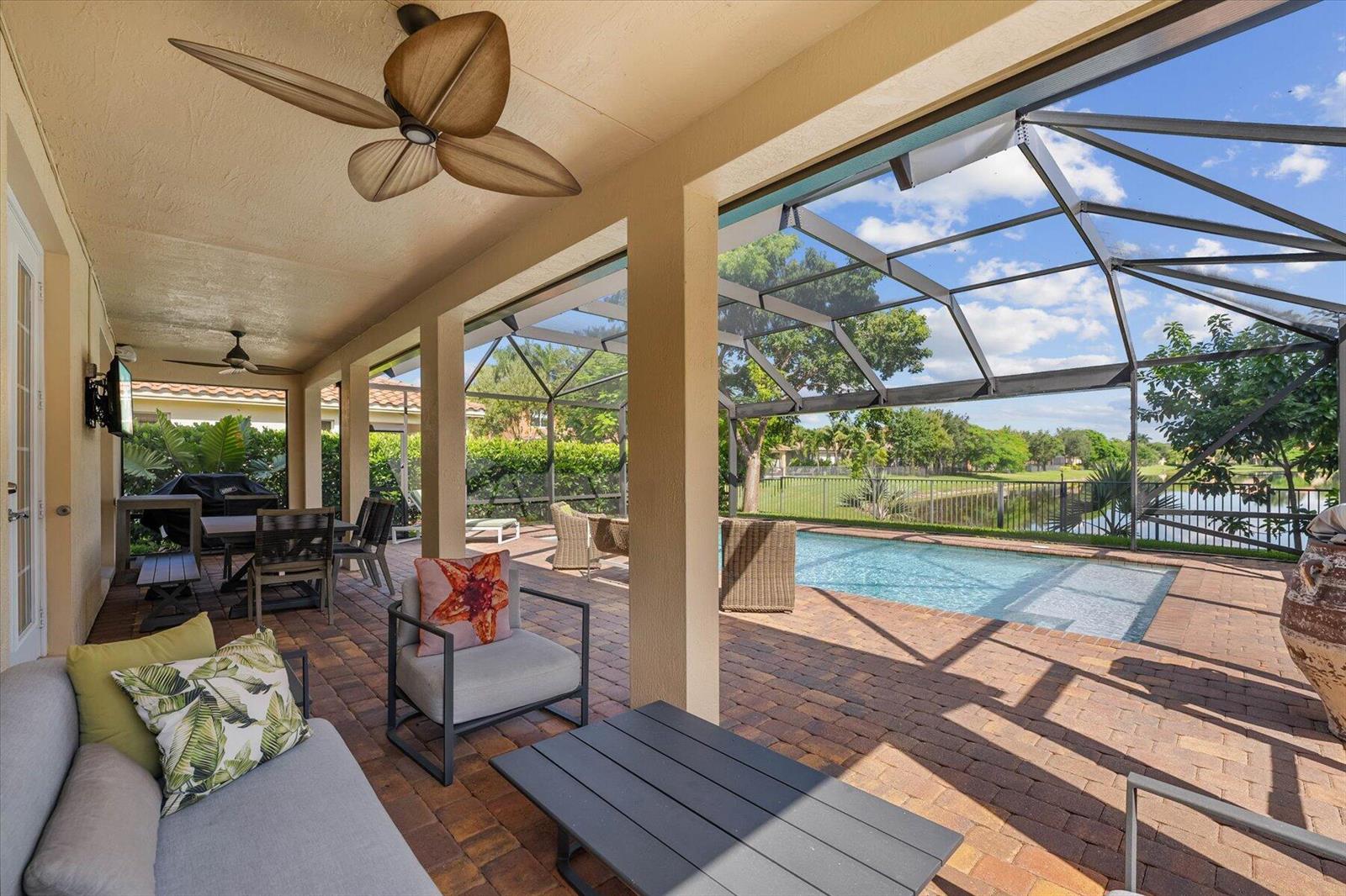 A covered patio features a ceiling fan, outdoor furniture, and a screened-in pool area — 10731 Ivanhoe Lane, Wellington FL 33414, WELLINGTON, FL