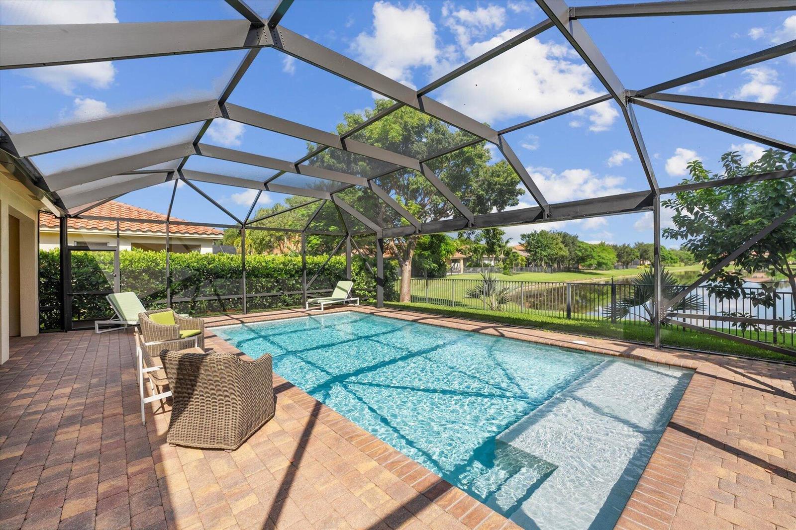 A screened-in patio features a rectangular swimming pool with a sun shelf and brick pavers — 10731 Ivanhoe Lane, Wellington FL 33414, WELLINGTON, FL