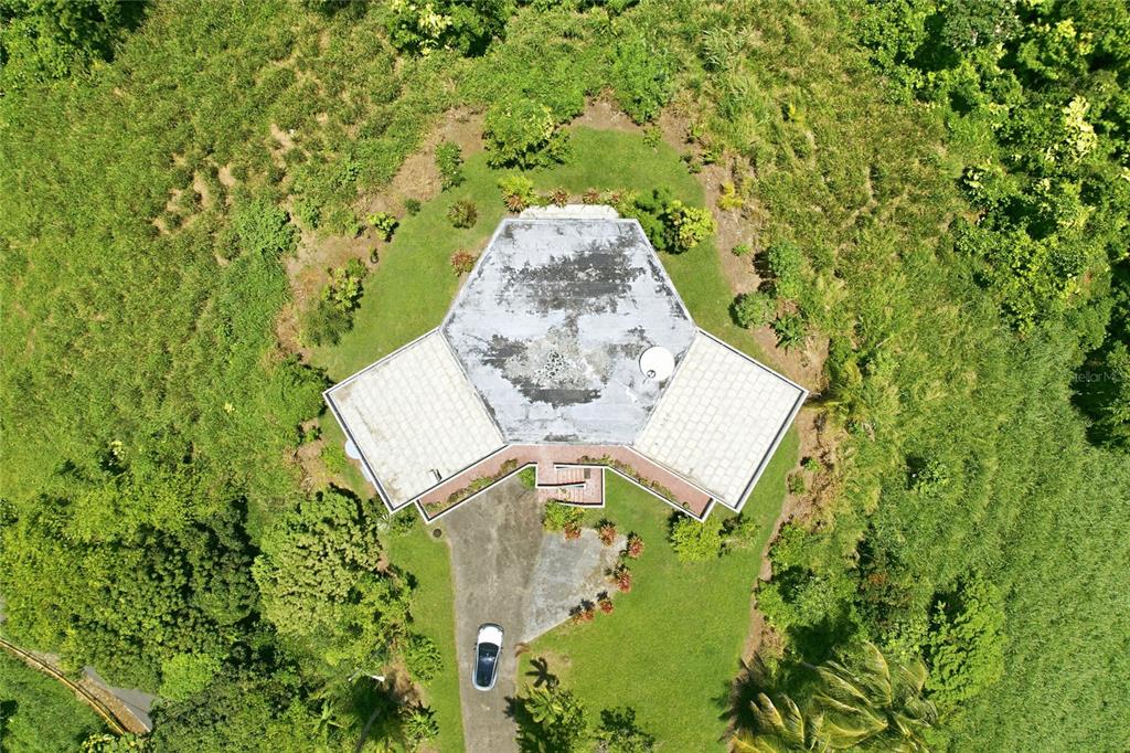 An aerial view shows a hexagonal house with a flat roof surrounded by lush greenery — 988 KM 1.5, LUQUILLO, PR