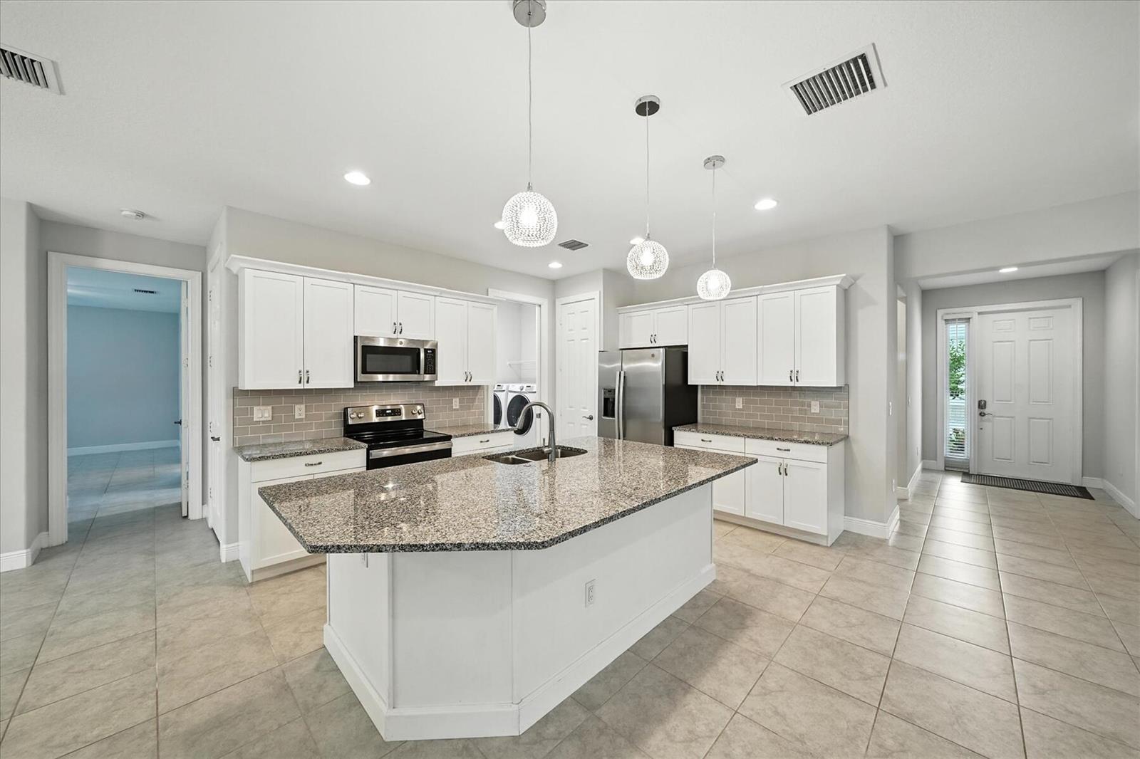 A kitchen with white cabinets, granite countertops, a central island, and stainless steel appliances — 6096 Bella Rosa Lane, Vero Beach FL 32966, VERO BEACH, FL