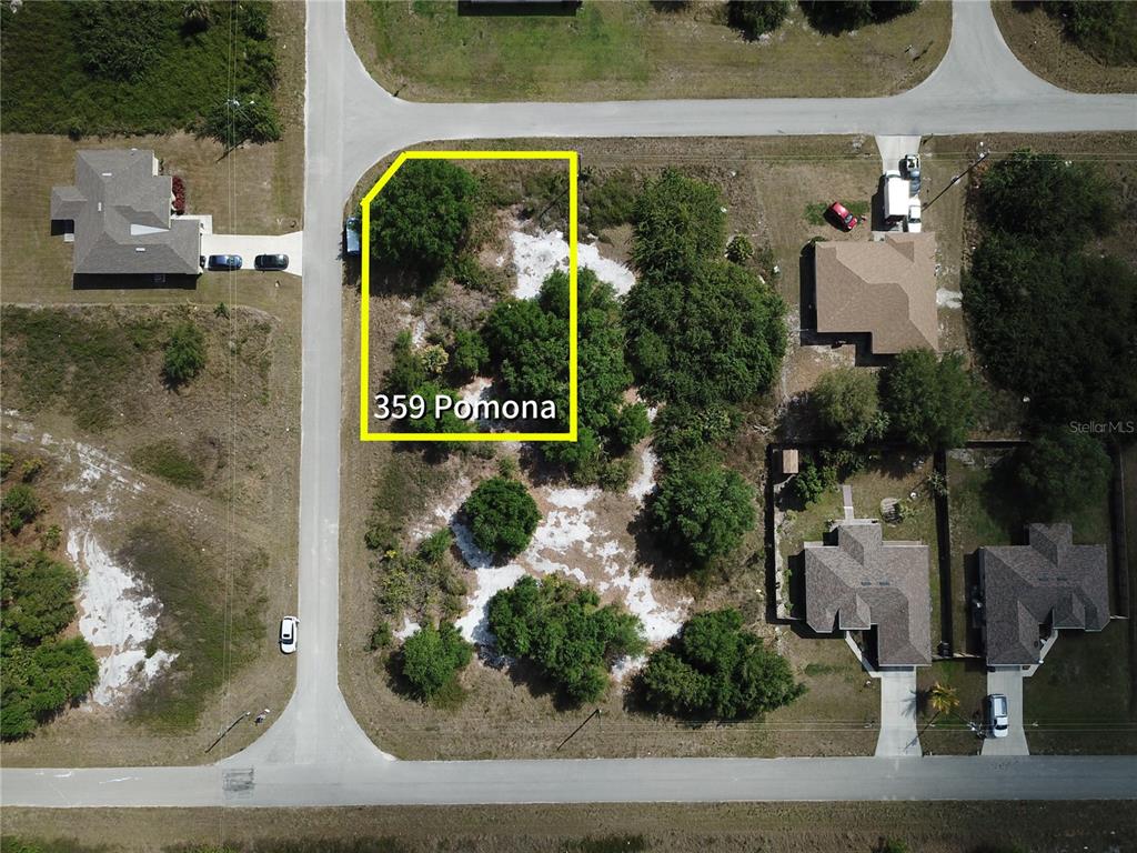 This aerial view shows a vacant residential lot outlined in yellow within a neighborhood — 359 POMONA STREET, LEHIGH ACRES, FL