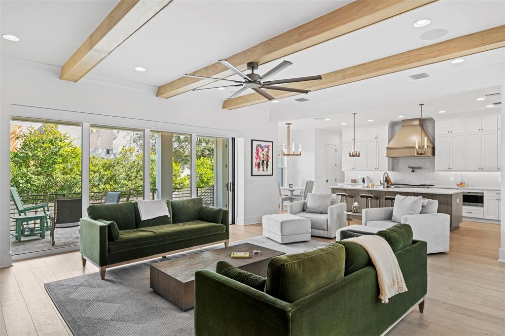 A living room with green sofas, wood ceiling beams, and an open kitchen beyond — 615 LUZON AVENUE, TAMPA, FL