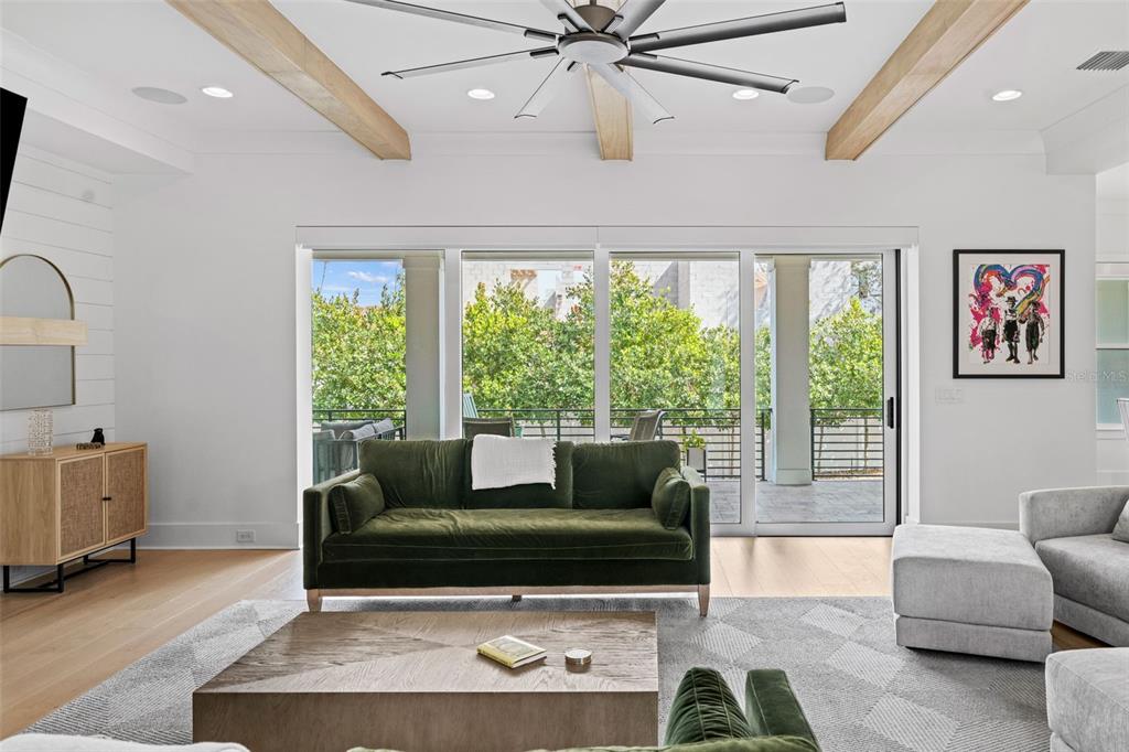 A living room features a green velvet sofa, wooden coffee table, and large sliding glass doors — 615 LUZON AVENUE, TAMPA, FL