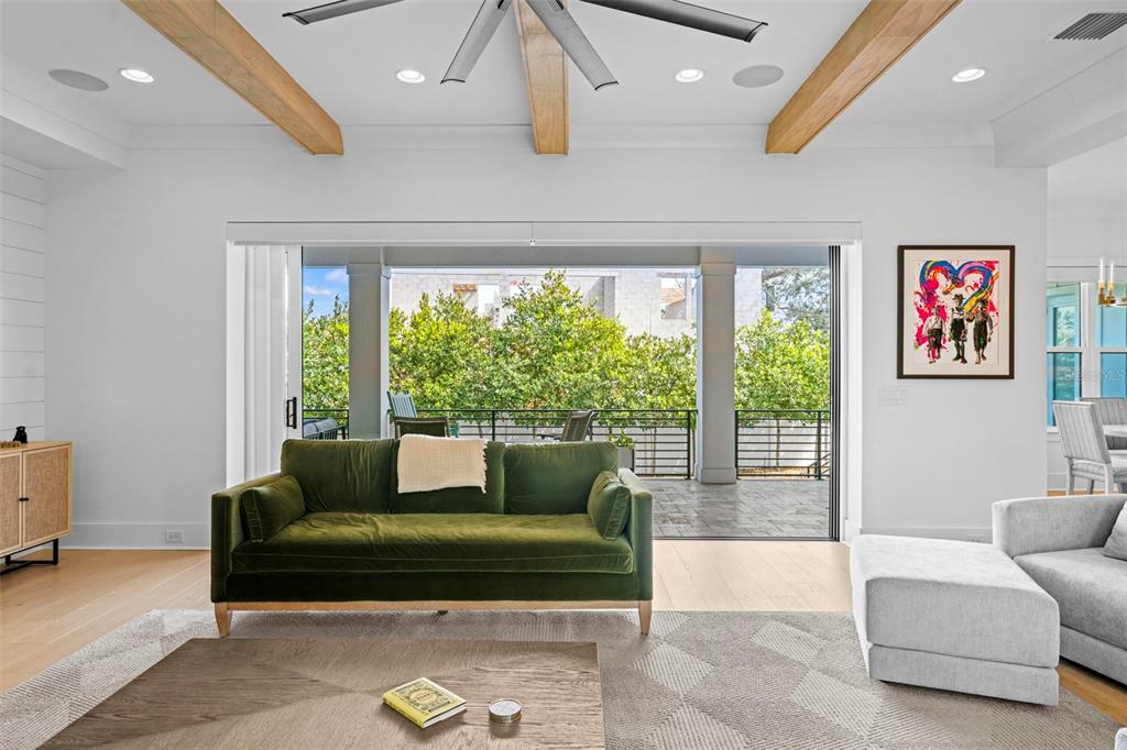 A living room features a green velvet sofa, wood ceiling beams, and sliding glass doors — 615 LUZON AVENUE, TAMPA, FL