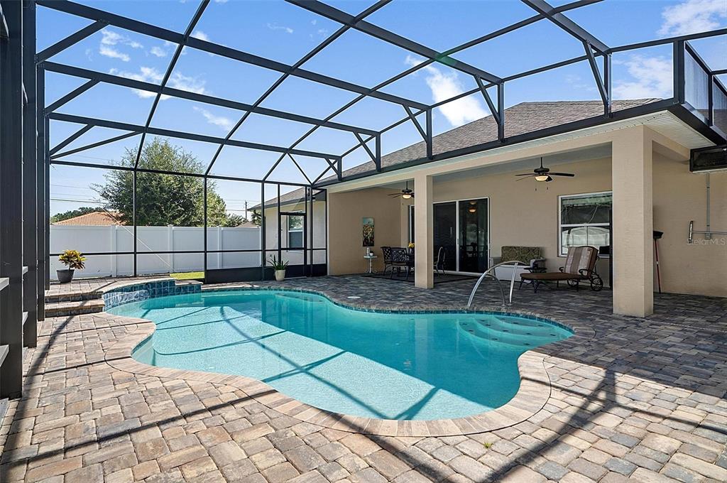 A swimming pool with a paver deck is enclosed by a screened lanai — 2 LYTTON LANE, PALM COAST, FL