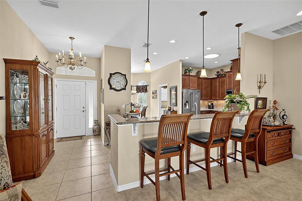 A kitchen with a breakfast bar, wooden stools, and an adjacent entryway with a chandelier — 2 LYTTON LANE, PALM COAST, FL
