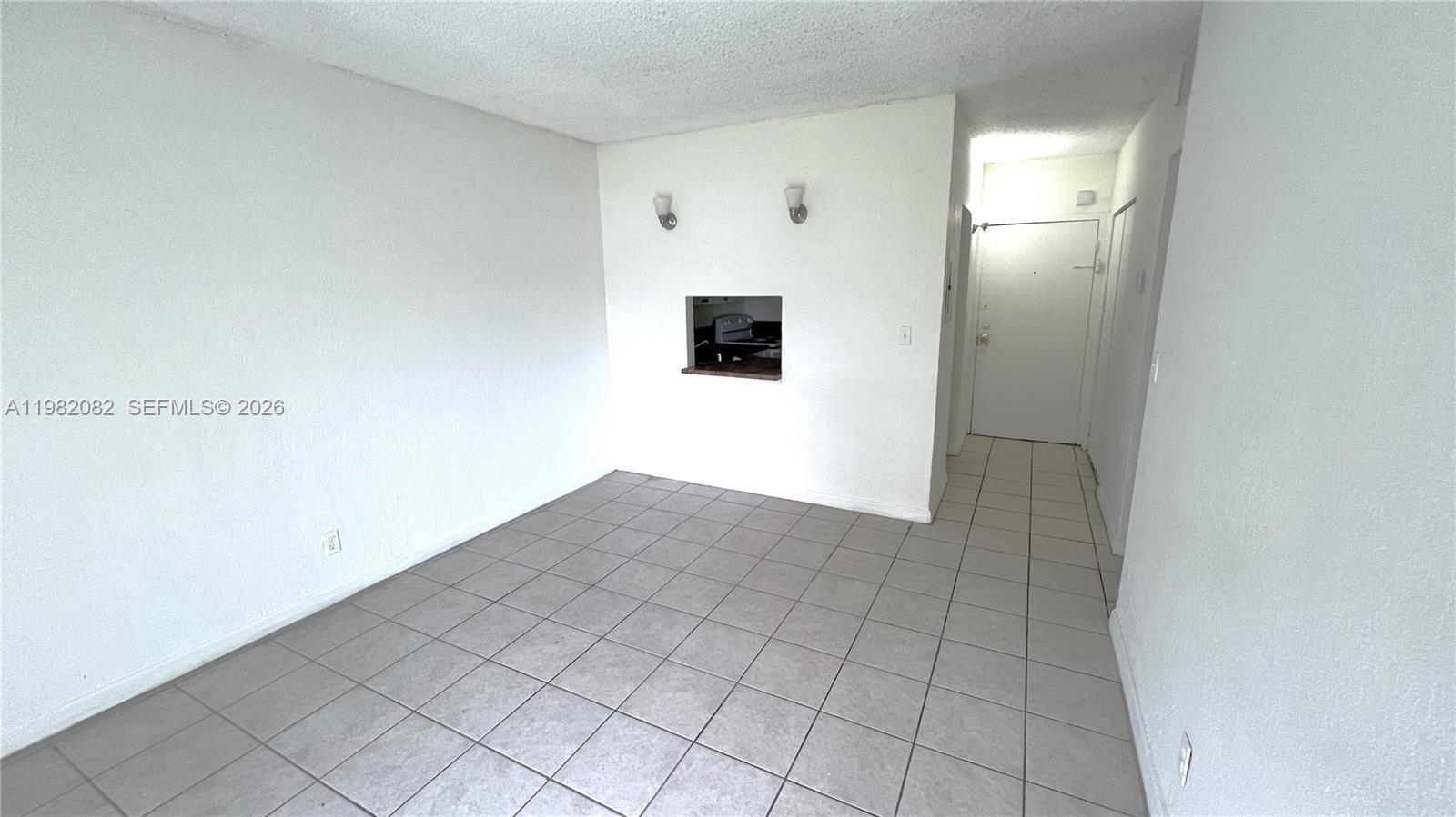 An empty room with white walls, tile flooring, and a kitchen pass-through window — 801 NW 47th Ave # 103W, Miami FL 33126, MIAMI, FL
