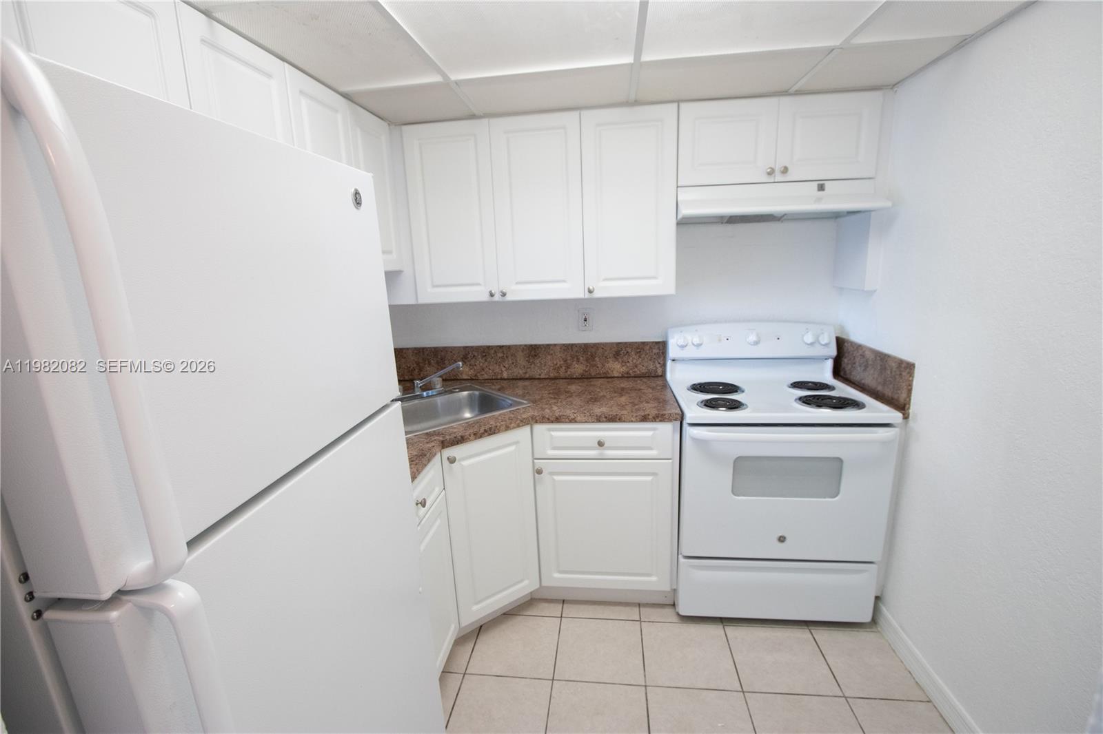 A small kitchen features white cabinets, white appliances, and brown laminate countertops — 801 NW 47th Ave # 103W, Miami FL 33126, MIAMI, FL