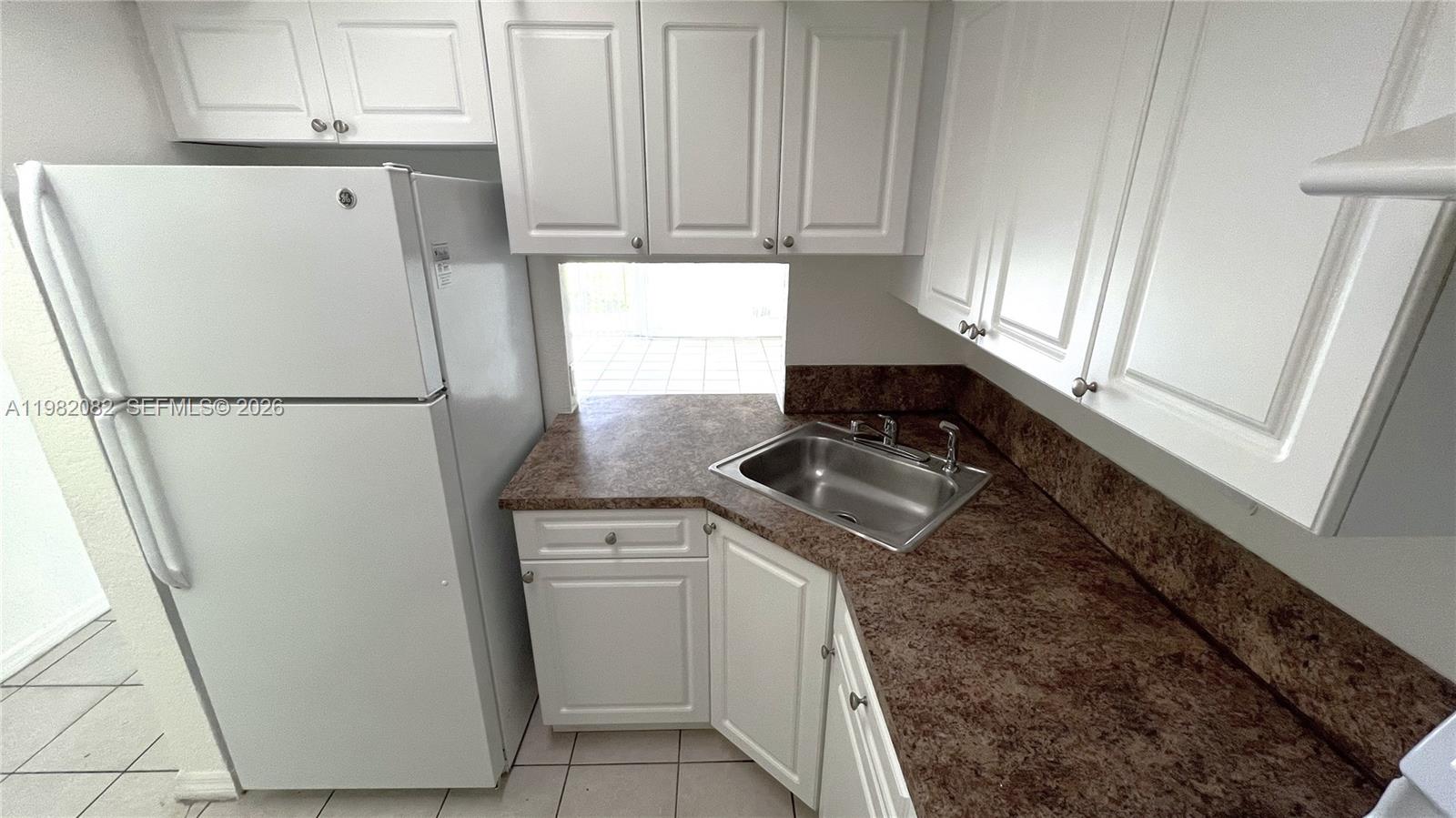 A kitchen features white cabinets, brown laminate countertops, a stainless steel sink, and a refrigerator — 801 NW 47th Ave # 103W, Miami FL 33126, MIAMI, FL