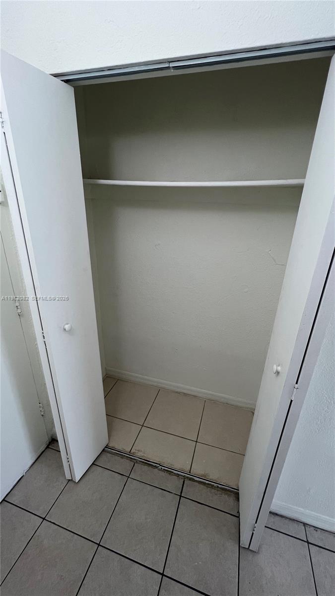 A closet with white bi-fold doors, a single shelf, and tiled flooring — 801 NW 47th Ave # 103W, Miami FL 33126, MIAMI, FL
