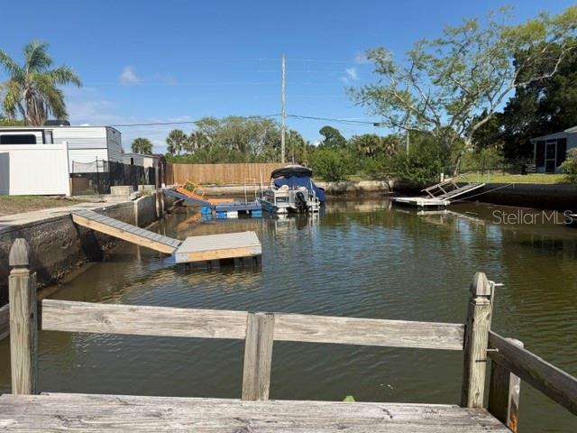 A view of a canal with a wooden dock, a boat, and a nearby trailer — 6832 ALBATROSS LANE, HUDSON, FL