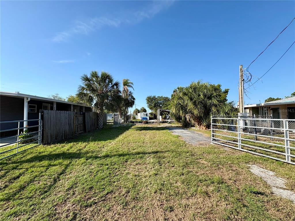 A grassy lot sits between two mobile homes with metal fencing on both sides — 6832 ALBATROSS LANE, HUDSON, FL
