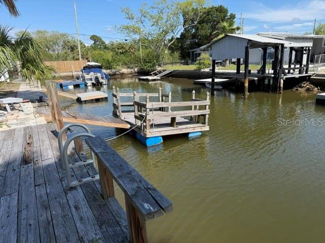A wooden dock with a floating platform extends into a canal near a boat lift — 6832 ALBATROSS LANE, HUDSON, FL
