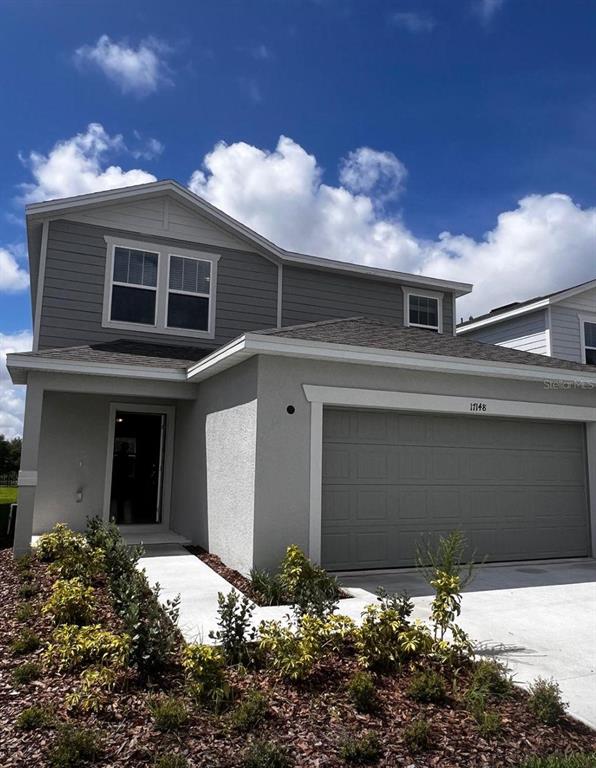 A living room features blue sofas, a matching armchair, a glass coffee table, and tile flooring — 17148 CAGAN CROSSINGS BOULEVARD, CLERMONT, FL