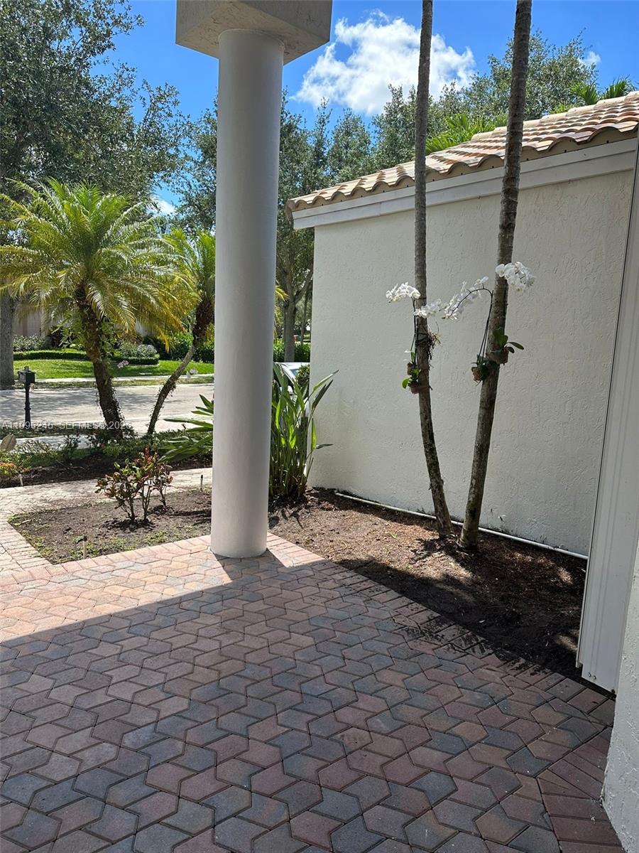 A paved patio area features a large white column and two palm trees with orchids — 3066 Lakewood Cir, Weston FL 33332, WESTON, FL