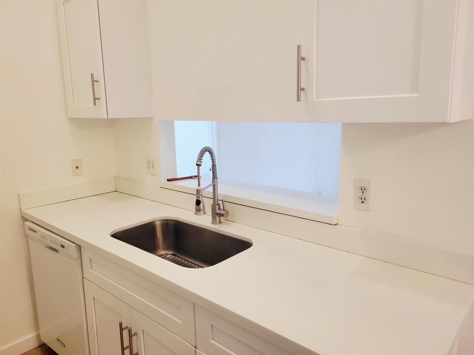 A kitchen features white cabinets, a stainless steel sink, and a white countertop — 6285 Chasewood Drive # F, Jupiter FL 33458, JUPITER, FL
