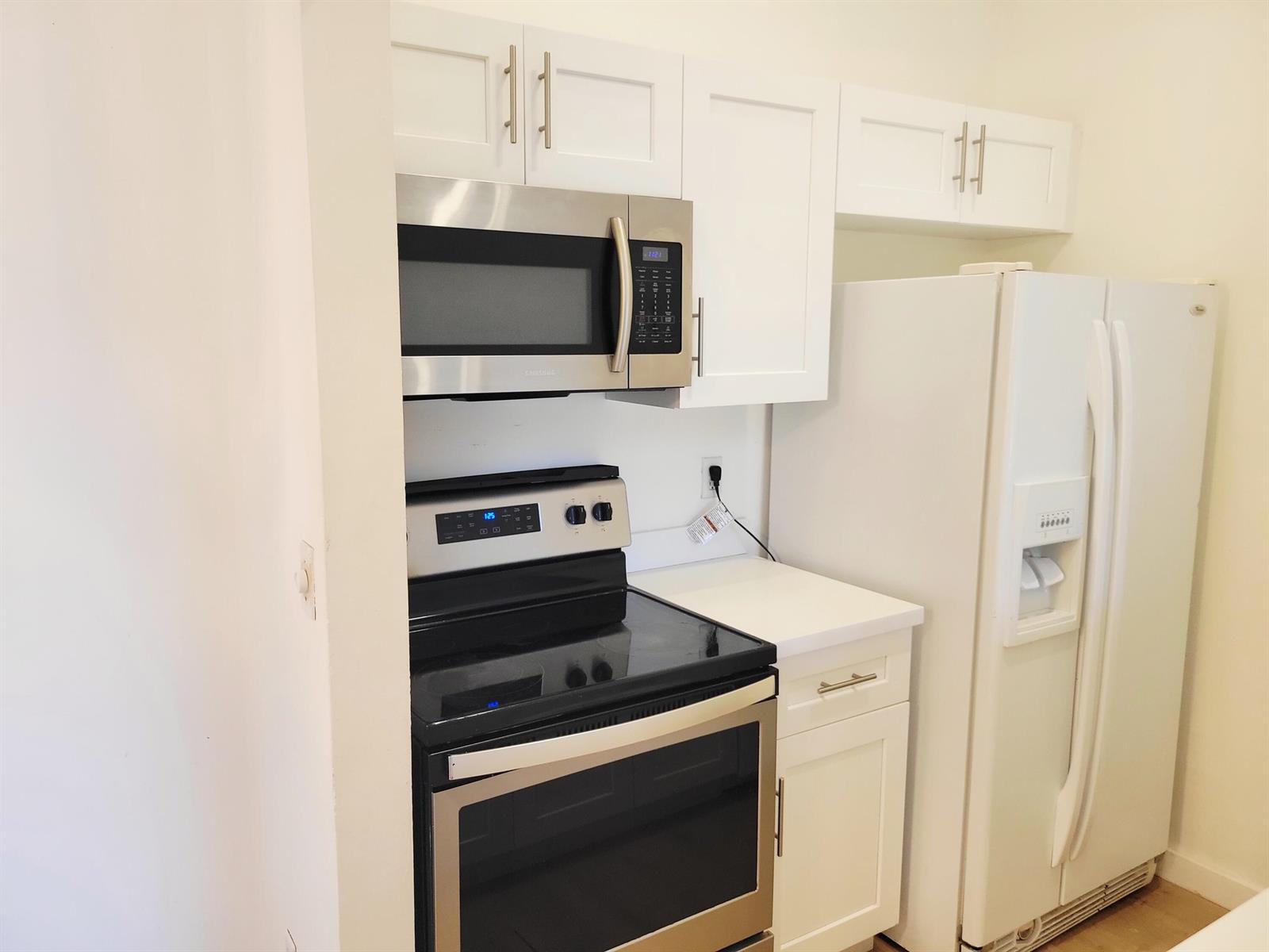 A kitchen features white cabinets, stainless steel appliances, and a white refrigerator — 6285 Chasewood Drive # F, Jupiter FL 33458, JUPITER, FL