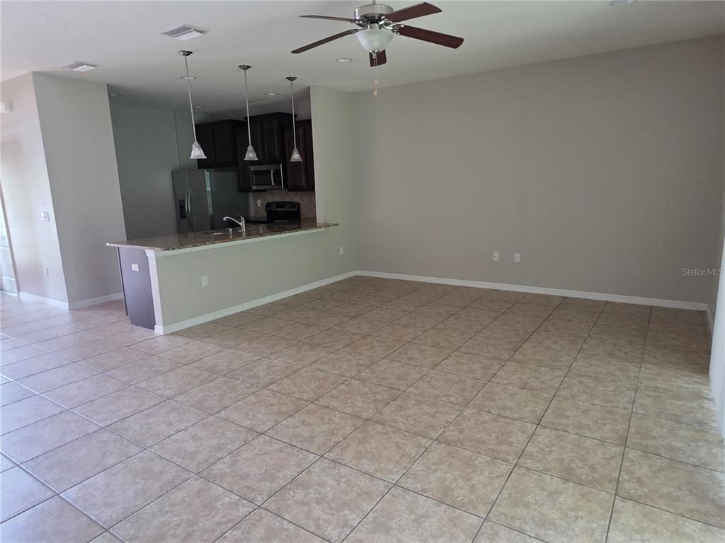 An open-concept living area features tile flooring, a kitchen island with pendant lights, and cabinetry — 8327 PINE RIVER ROAD, TAMPA, FL