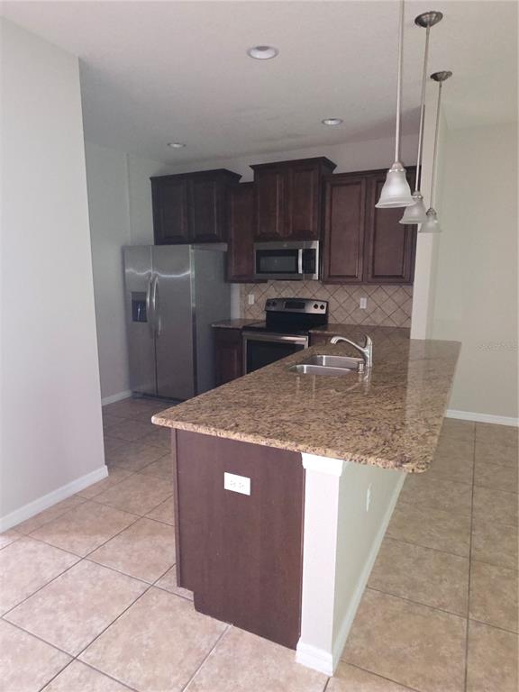 A kitchen features dark wood cabinets, granite countertops, stainless steel appliances, and a central island — 8327 PINE RIVER ROAD, TAMPA, FL