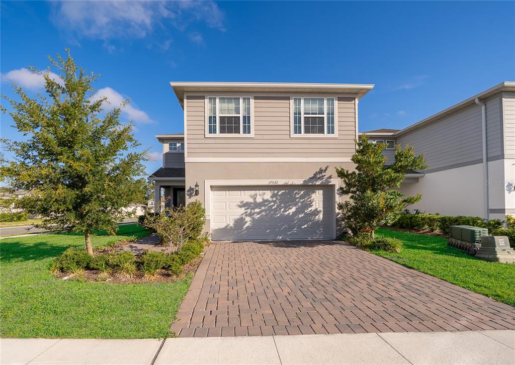 A covered brick patio overlooks a grassy suburban lawn and neighboring houses — 17532 SAW PALMETTO AVENUE, CLERMONT, FL