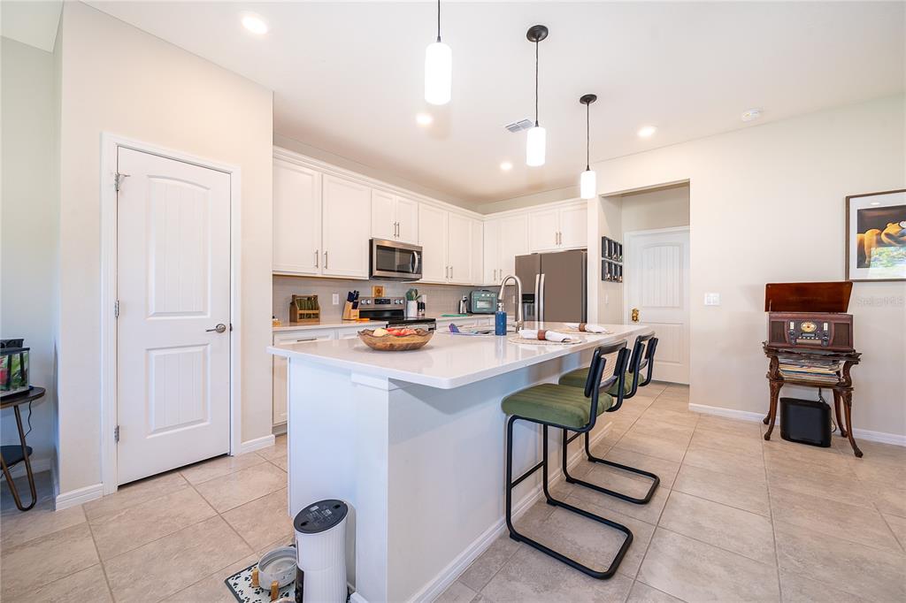 A modern kitchen features white cabinets, a large island with a sink, and stainless steel appliances — 17532 SAW PALMETTO AVENUE, CLERMONT, FL