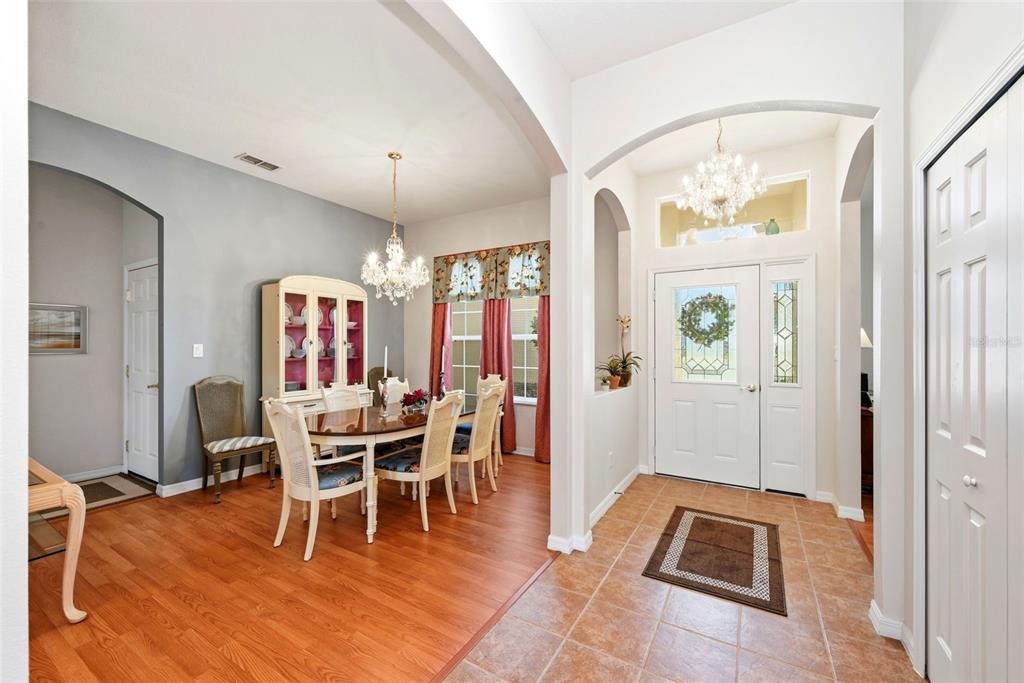 A dining room with wood floors and a chandelier sits beside a tiled entryway — 3810 ST EMMA COURT, LEESBURG, FL
