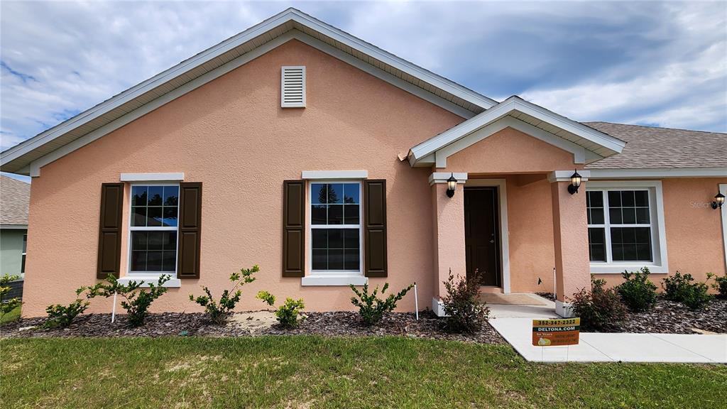 A peach-colored single-story house features brown shutters, a covered entryway, and a landscaped front yard — 680 W MARGUERITA DRIVE, DUNNELLON, FL