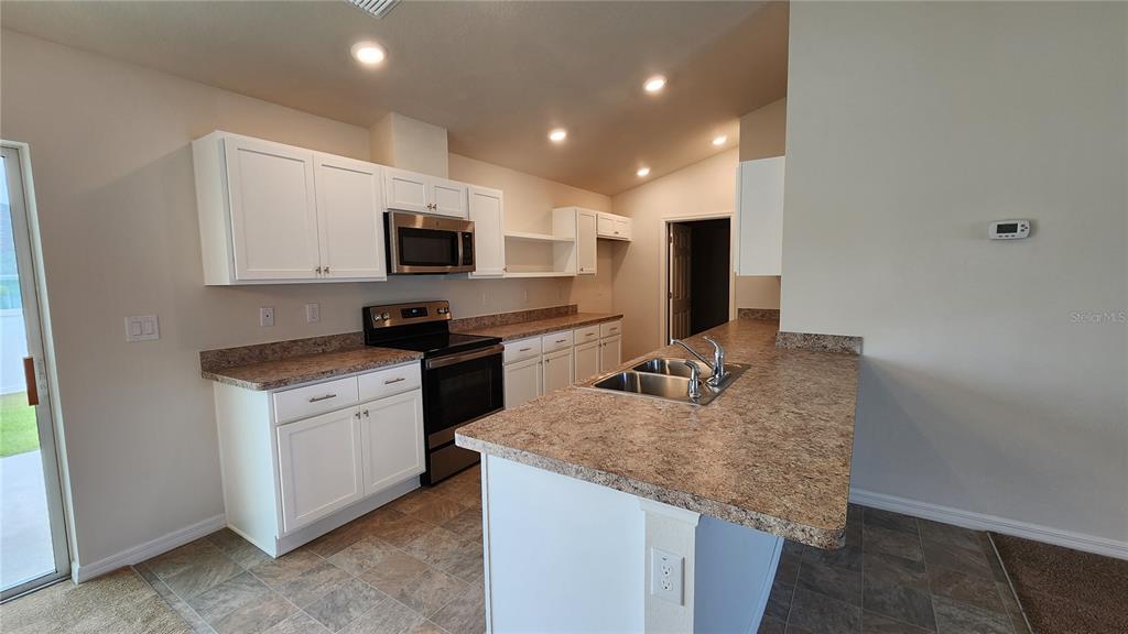 A kitchen features white cabinets, laminate countertops, stainless steel appliances, and a central island — 680 W MARGUERITA DRIVE, DUNNELLON, FL