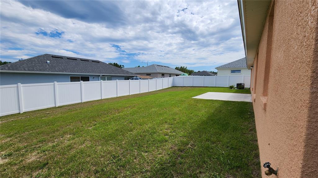 A backyard with a concrete patio, green grass, and a white vinyl privacy fence — 680 W MARGUERITA DRIVE, DUNNELLON, FL