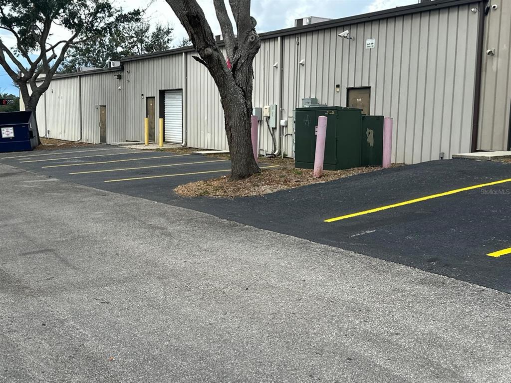 An exterior view of a commercial building with parking spaces, a tree, and utility equipment — 1727 E BUSCH BOULEVARD, TAMPA, FL