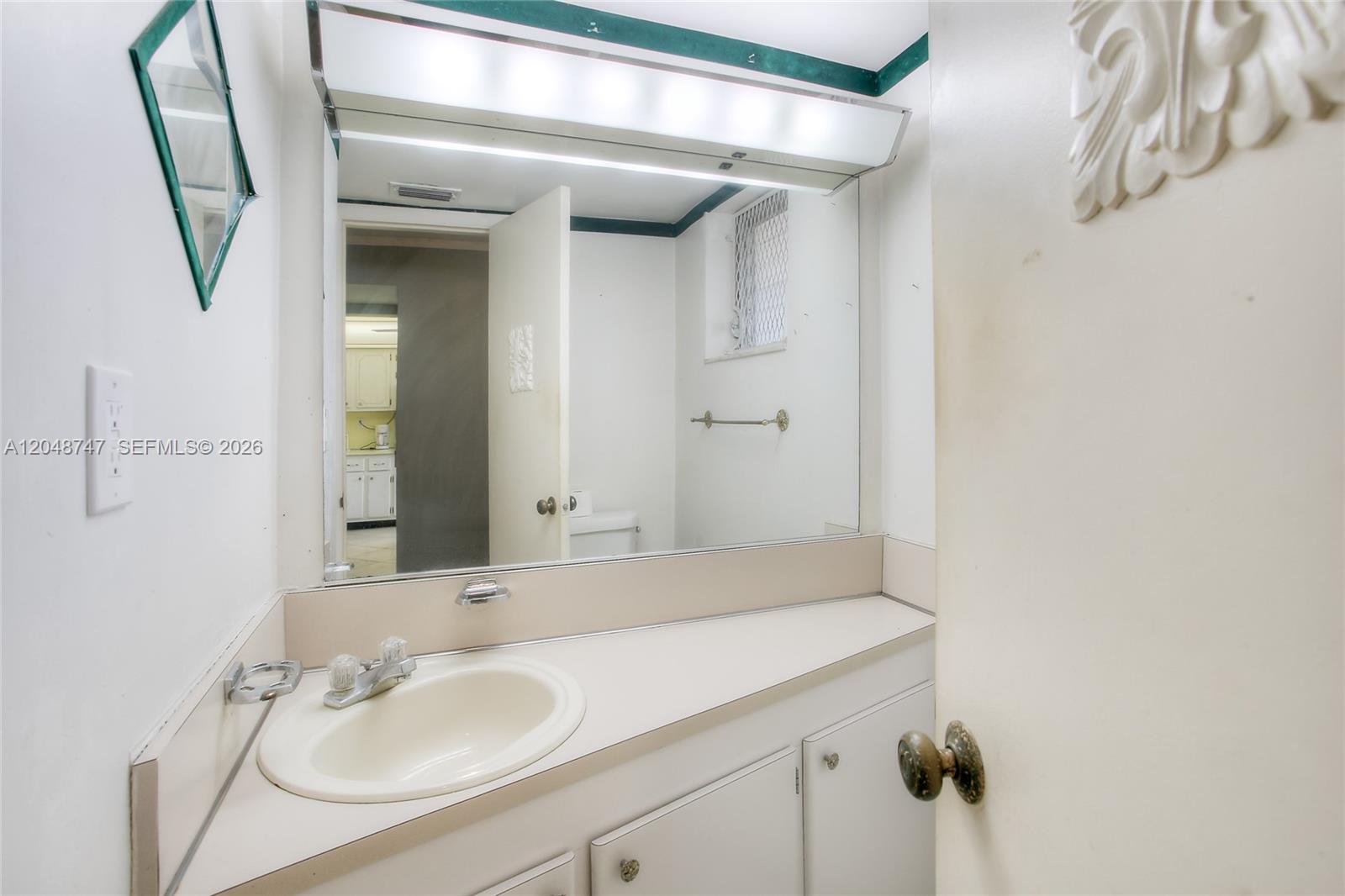 A bathroom features a white vanity, a large wall mirror, and a light fixture — 1501 NE 191st St # C106, Miami FL 33179, MIAMI, FL