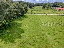 An aerial view shows a large, grassy field bordered by trees and a distant house — CR 763, BUSHNELL, FL