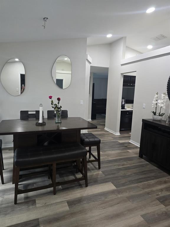 An interior view of a room with wood-look flooring and a doorway leading to a kitchen — 13303 PINYON DRIVE, CLERMONT, FL
