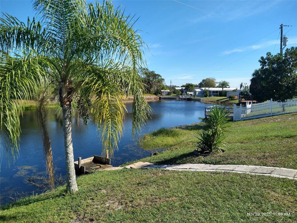 A palm tree stands near a pond with a small wooden dock and white fencing — 8454 BREEZE HILL DRIVE, LAKE WALES, FL