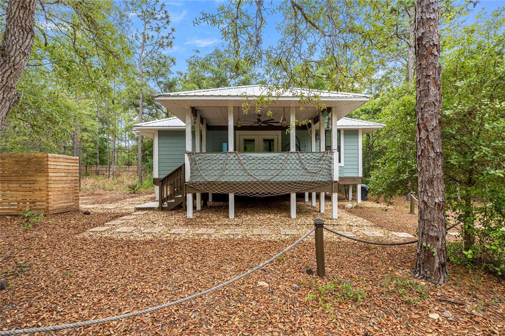 A light green cottage with a metal roof and a screened porch sits in woods — 414 S SCHOOL AVENUE, LECANTO, FL