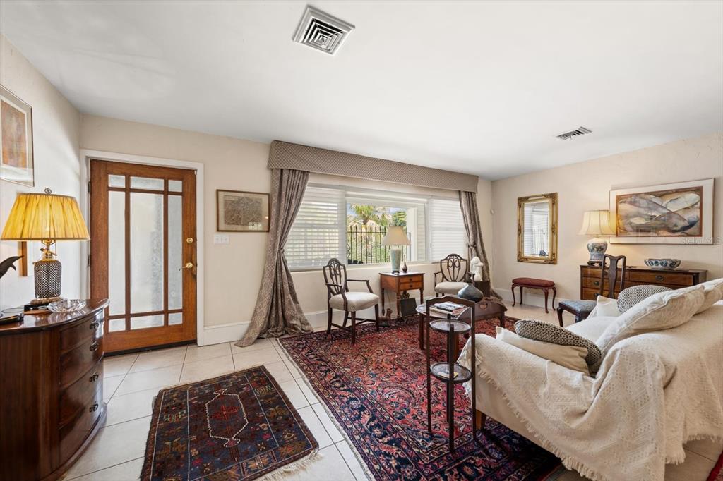 A living room with tile floors, a large area rug, and a front entry door — 109 PONCE DE LEON BOULEVARD, BELLEAIR, FL