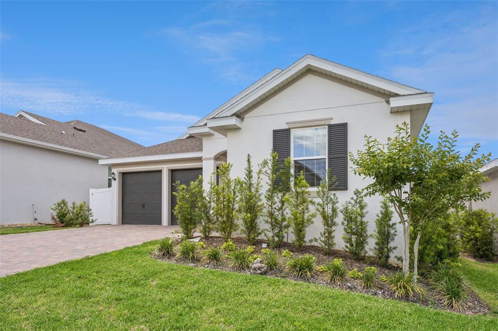 A single-story house with a two-car garage, white stucco exterior, and a landscaped front yard — 2101 AXEL STREET, CLERMONT, FL