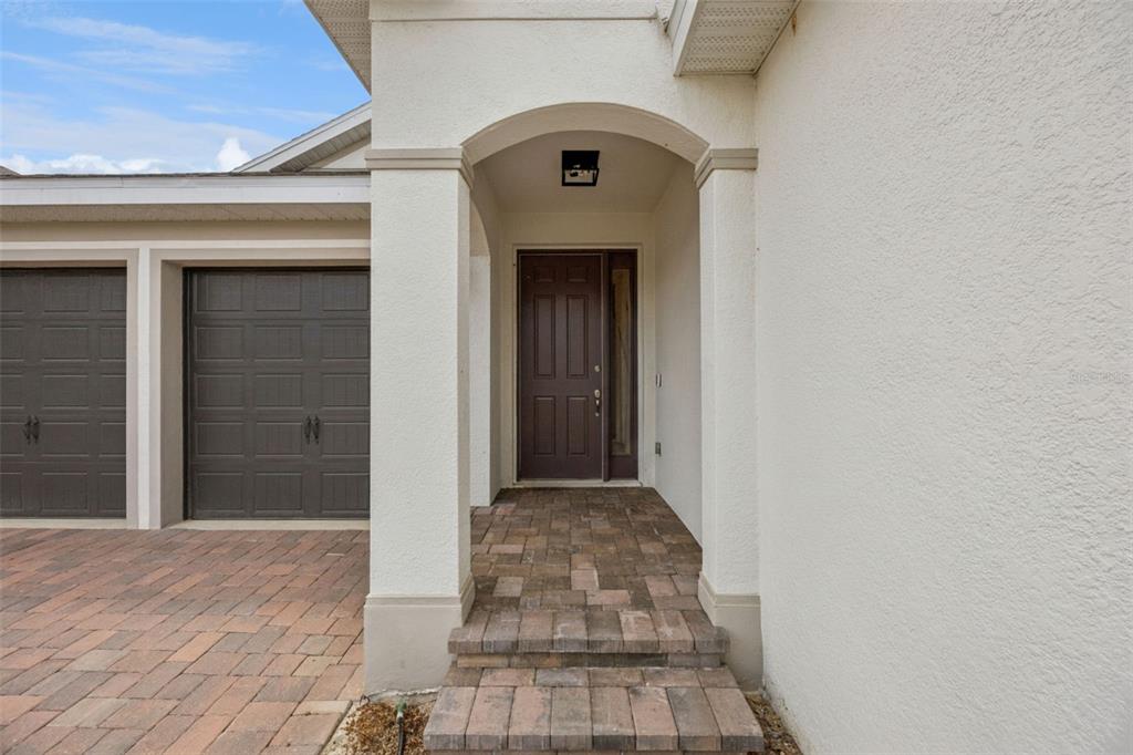 The exterior entrance features a dark brown front door, arched entryway, and paver walkway — 2101 AXEL STREET, CLERMONT, FL