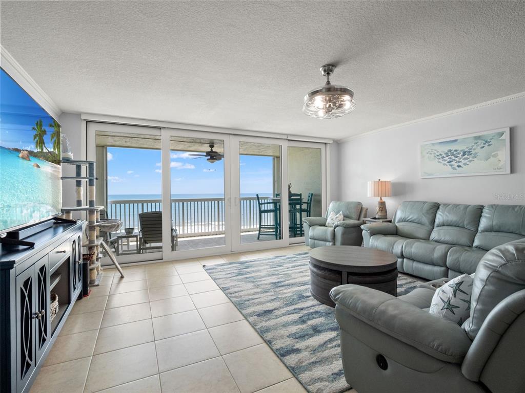 A living room features light tile floors, a blue area rug, and sliding glass balcony doors — 407 HIGHWAY A1A UNIT 443, SATELLITE BEACH, FL