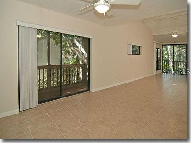 An interior view of a room with tile flooring, sliding glass doors, and ceiling fans — 1508 PELICAN COVE ROAD UNIT 238, SARASOTA, FL