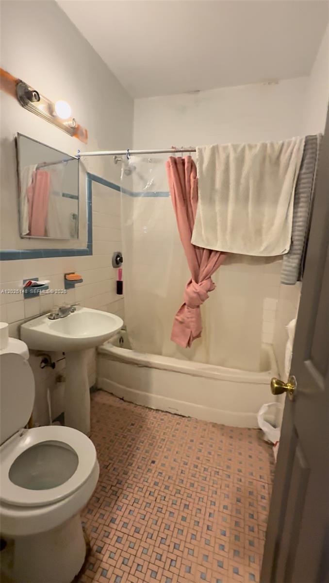A bathroom features a pedestal sink, a toilet, and a shower-tub combination with tile walls — 110 NW 52nd St, Miami FL 33127, MIAMI, FL