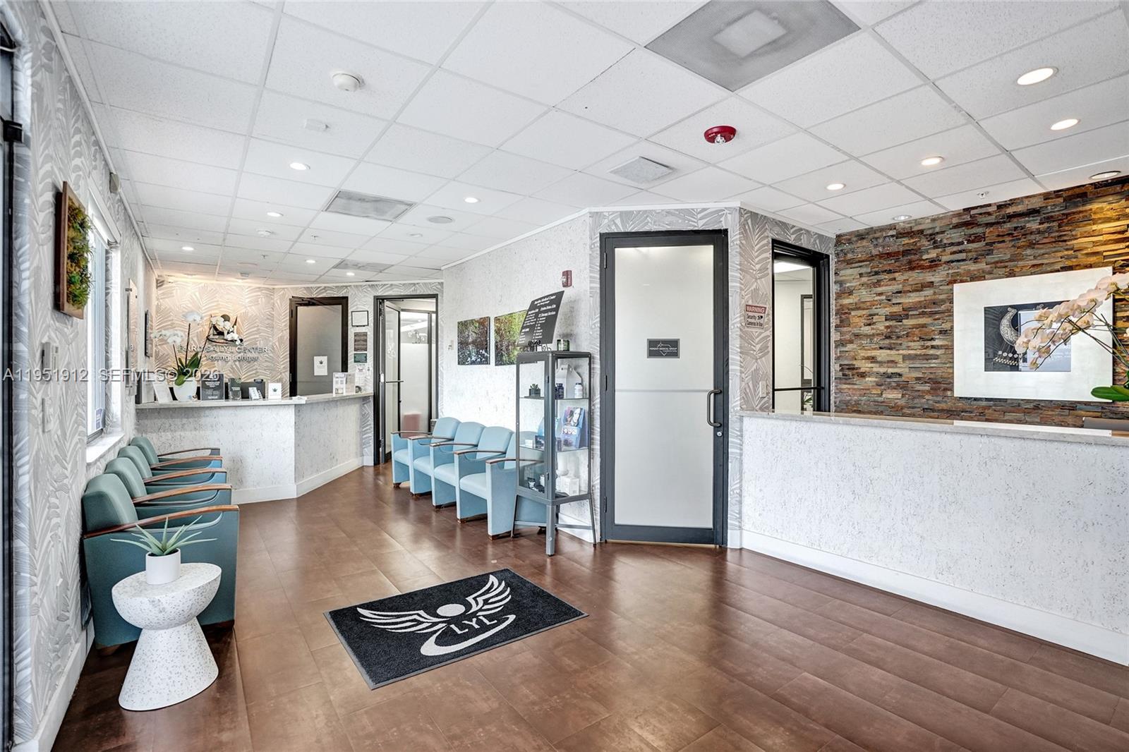 A medical office waiting room features light blue chairs, a reception desk, and stone wall accents — 7374 SW 93rd Ave # B, Miami FL 33173, MIAMI, FL