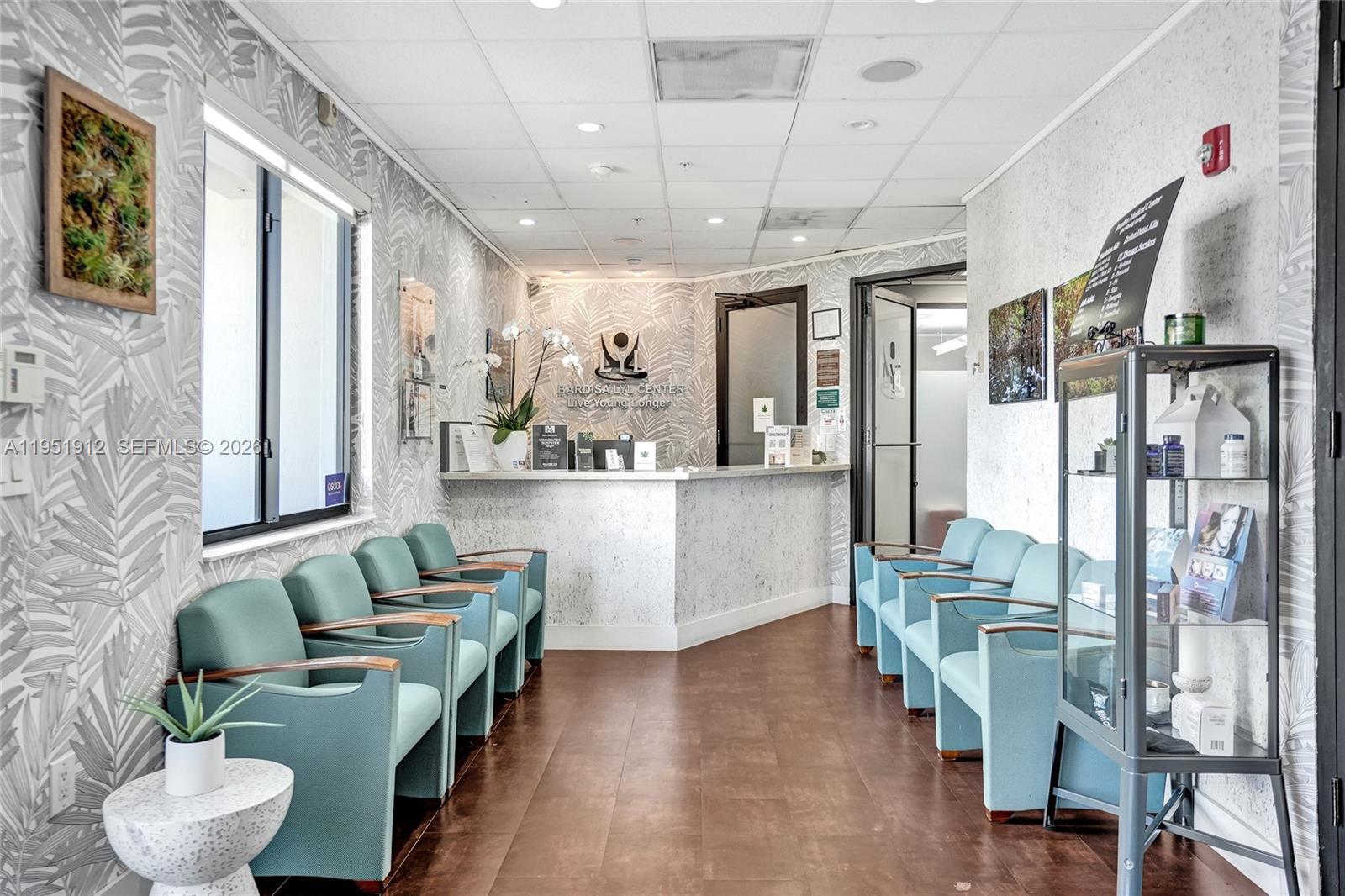 A waiting room features teal chairs, patterned wallpaper, a reception desk, and a display cabinet — 7374 SW 93rd Ave # B, Miami FL 33173, MIAMI, FL